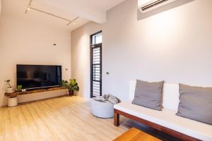 a living room with a white couch and a flat screen tv at Lainandao Villa in Hengchun