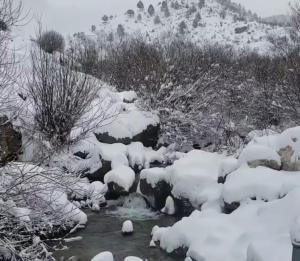 a creek covered in snow next to a mountain at Guest House Korabi in Ceren