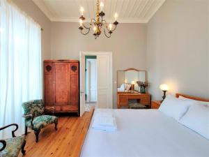 a bedroom with a large white bed and a chandelier at Spiti Sea View Neoclassical House in Stenies in Andros