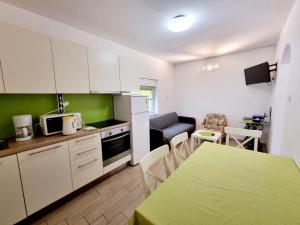 a kitchen with white cabinets and a table and a dining room at ARA-ZAROK in Baška