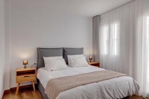 a bedroom with a large bed and two windows at Marion Suite in Ermoupoli