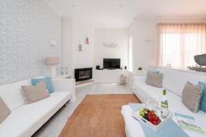 ein Wohnzimmer mit weißen Sofas und einem TV in der Unterkunft Lilies Villa - BlueSea in Albufeira