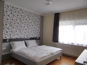 1 dormitorio con 1 cama con un mural en la pared en Alfa apartman, en Sárvár