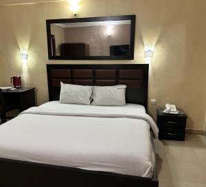 ein Schlafzimmer mit einem großen Bett und einem Spiegel an der Wand in der Unterkunft Whitehouse Msquare Hotel in Ikeja