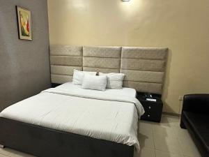 a bedroom with a large bed with white sheets and pillows at Whitehouse Msquare Hotel in Ikeja