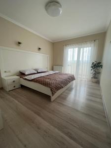 een witte slaapkamer met een bed en een houten vloer bij Затишні апартаменти TWO in Tsjernivsi