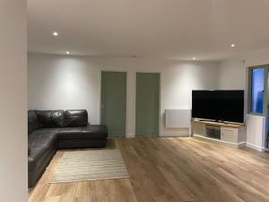 a living room with a black leather couch and a flat screen tv at Poplar holiday cottage in Moulton Chapel