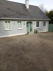 a white house with a green door and a driveway at Applelea House in Rosslare