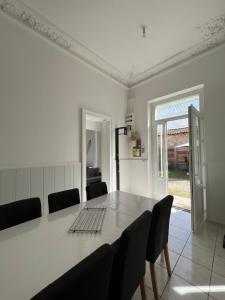 a white dining room with a table and chairs at Charmante maison au cœur du medoc in Cussac-Fort-Medoc +4 photos