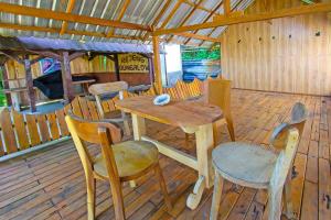 een houten tafel en stoelen op een houten terras bij OYO 92419 Rejeng Homestay Near Kerta Gangga Waterfall in Luk