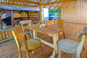 een houten tafel en stoelen op een houten terras bij OYO 92419 Rejeng Homestay Near Kerta Gangga Waterfall in Luk