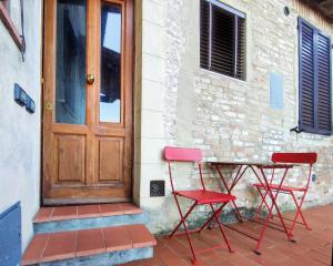 Casa Matteo San Gimignano Apartments في سان جيمنيانو: كرسيين احمر وطاولة امام باب