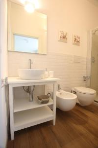een badkamer met een wastafel, een toilet en een spiegel bij Villa Teresa Maria in Porto Cesareo