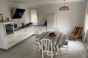 a white kitchen with a table and chairs in it at Spacious apartment in the heart of Narbonne Plage in Narbonne