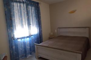 a bedroom with a bed and a window with blue curtains at Spacious apartment in the heart of Narbonne Plage in Narbonne