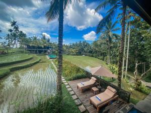 a resort with two lounge chairs and a pond at Uma Giri Villas Ubud by Pramana Villas in Ubud