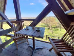 - une table et des chaises en bois sur une terrasse couverte avec vue dans l'établissement D'Hauville Vallée, à Bonneville-la-Louvet