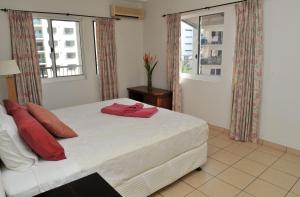 a bedroom with a bed with red pillows on it at Inner city Cardona Court apartment in Darwin
