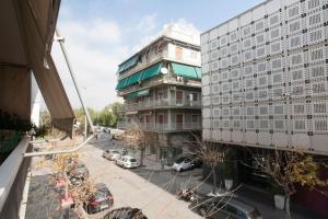 a tall building with cars parked in a parking lot at Modern flat in city center in Athens