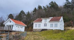 zwei weiße Häuser auf einem Hügel in der Unterkunft Molandstveit in Osestad