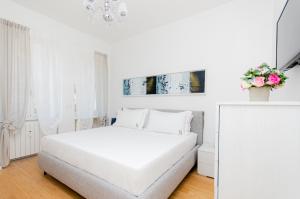 Habitación blanca con cama blanca y lámpara de araña. en Schiaparelli 4, en Milán