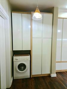 - un lave-linge et un sèche-linge dans une cuisine avec des placards blancs dans l'établissement Luxury Residence Apartment, à Tirana