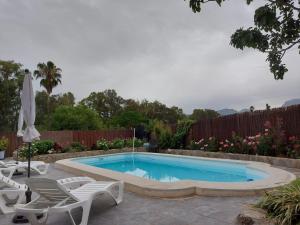 - une piscine dans une cour avec 2 chaises et un parasol dans l'établissement Vivienda Rural Sierra de Cádiz, Cabeza del Rey, à Prado del Rey