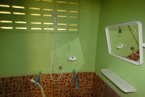 a green bathroom with a shower and a mirror at Ao Yai Homestay in Ban Ao Yai