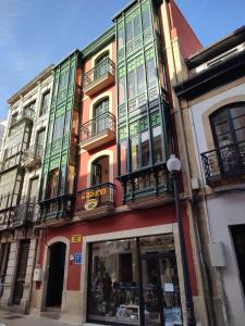 a building with colorful windows and balconies on a street at Hostal la Fruta Nueva apertura in Avilés