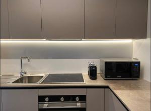 a kitchen with a sink and a microwave at Grazioso appartamento con giardino privato in Asti