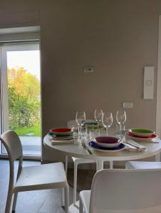 una mesa blanca con platos y copas de vino. en Grazioso appartamento con giardino privato en Asti