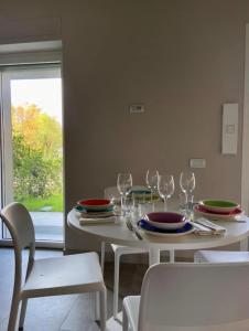 a white table with plates and wine glasses on it at Grazioso appartamento con giardino privato in Asti
