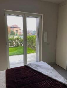 1 dormitorio con 1 cama y puerta corredera de cristal en Grazioso appartamento con giardino privato en Asti