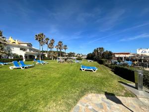 un parco con sedie a sdraio blu e palme di Cabopino Port - EaW Homes a Marbella