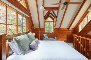 een slaapkamer met een bed in een kamer met ramen bij Fernhem Cottages- Love in the Mist in Emerald