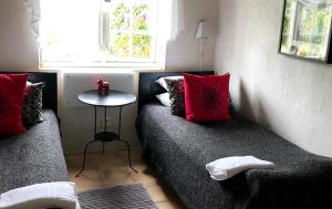 HammenhögにあるSödergårda Östra Bed & Breakfastの赤い枕とテーブル付きのベッド2台が備わる客室です。