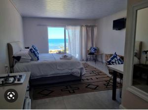 a bedroom with a bed and a view of the ocean at Lambertsbay Beachfront in Lambertʼs Bay