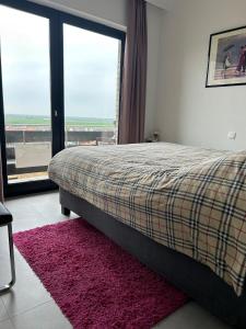 a bedroom with a bed and a large window at Appartement met 2 slaapkamers op zeedijk Middelkerke in Middelkerke