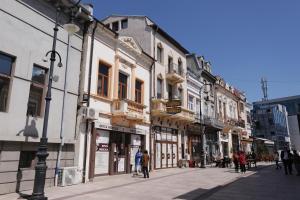 une rue avec des bâtiments et des gens qui marchent dans la rue dans l'établissement CENTRAL VIEW Craiova, à Craiova