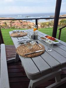 a picnic table with food on a balcony with the ocean at Lambertsbay Beachfront in Lambertʼs Bay