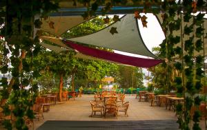 an outdoor patio with tables and chairs and trees at Pappi Chulo Morjim in Morjim