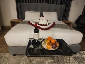 a tray with a plate of fruit and wine glasses on a bed at Lotus Boutique Hotel in Bethlehem