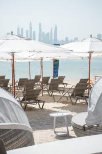 Wyndham Residences The Palm في دبي: مجموعة من الكراسي والمظلات على الشاطئ