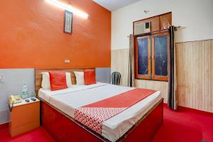 1 dormitorio con 1 cama con paredes de color naranja y ventana en OYO Hotel Fridays, en Bathinda