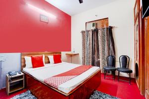 una camera rossa con un letto e due sedie di OYO Hotel Fridays a Bathinda