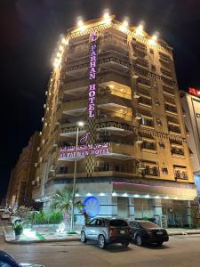 Al Farhan Hotel Suites Al siteen في الجبيل: مبنى كبير فيه سيارات تقف امامه