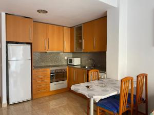 cocina con mesa y nevera blanca en Joan XXIII Apartment, en Tarragona