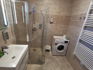 a bathroom with a shower and a washing machine at Moon Light in Hévíz