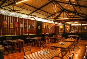 an empty restaurant with wooden tables and chairs at Pappi Chulo Morjim in Morjim