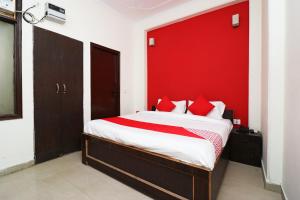 a bedroom with a bed with a red wall at OYO Hotel Grand Casa Near Aravali Biodiversity Park in Gurgaon